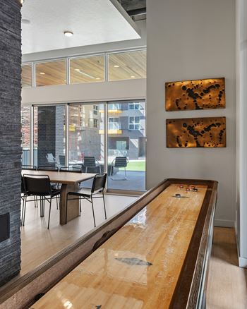 A shiny wooden air hockey table in a room with a glass wall.